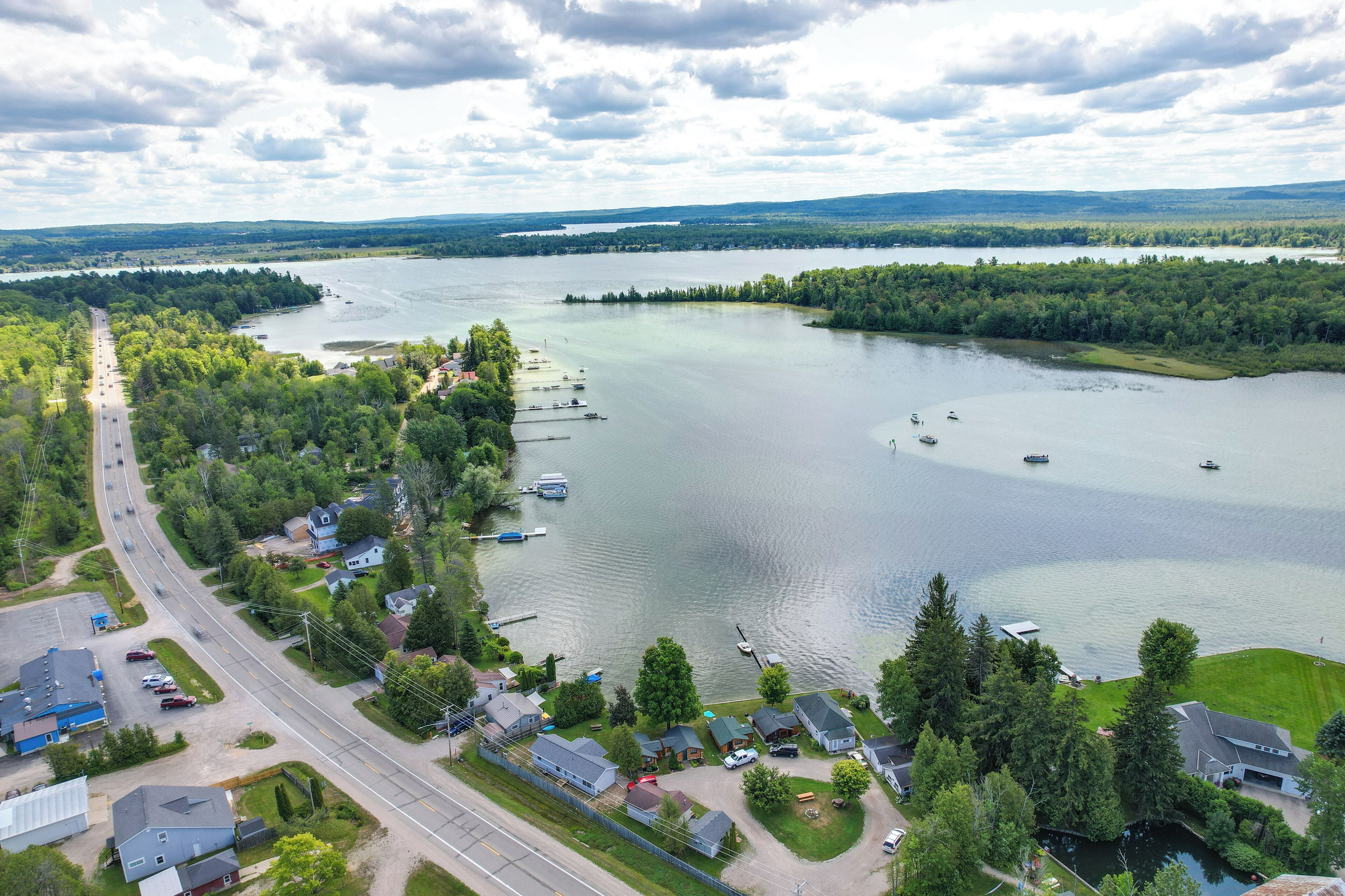 An aerial view of a lakeside community with houses, a road, and boats on the water.