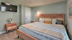 Ein Schlafzimmer mit Bett, Nachttisch und Wand-Fernseher.