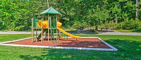 A playground with a green-roofed playhouse and two slides.