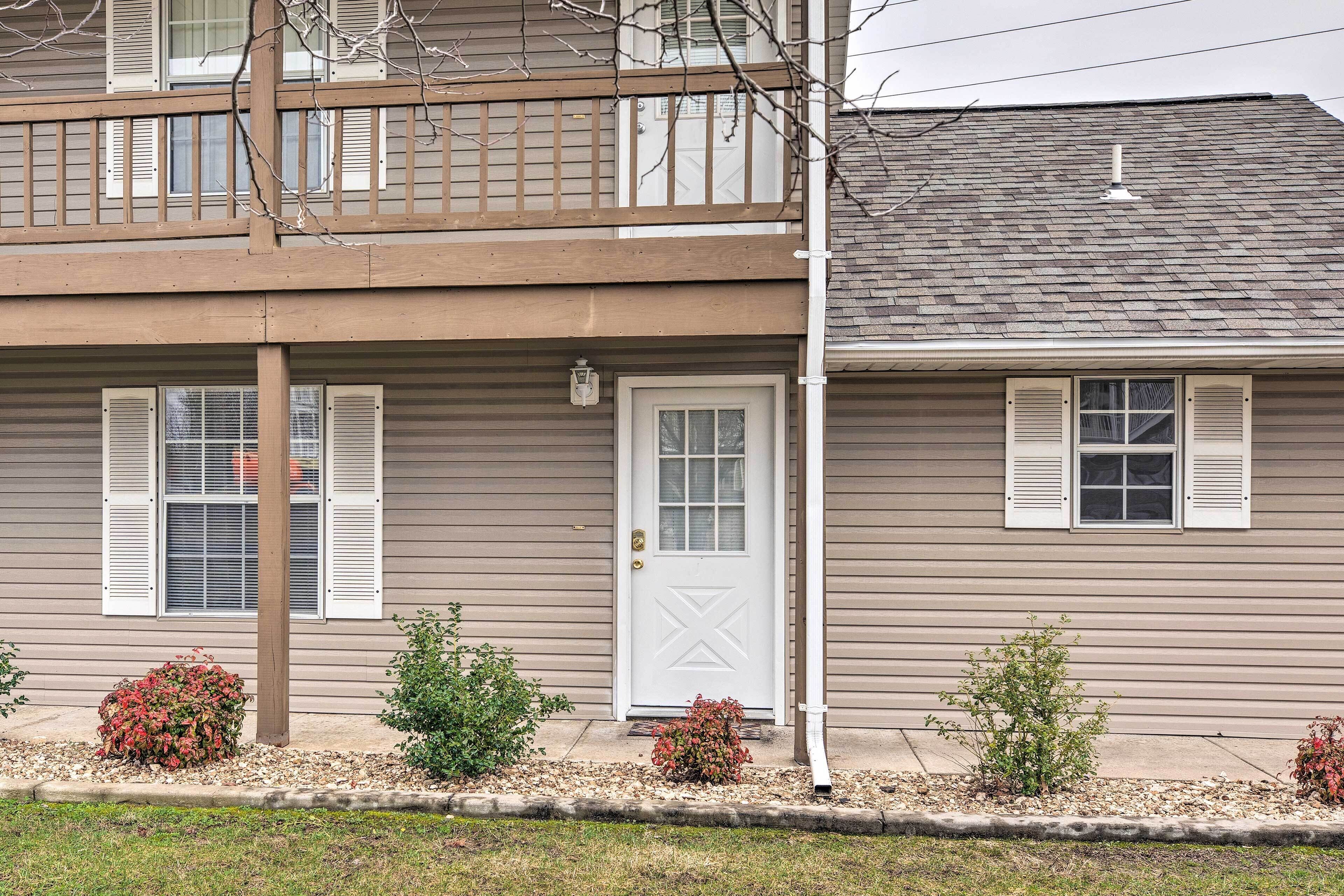 A two-story house with a front door, white shutters, and a small porch.
