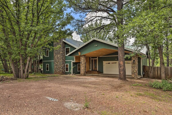 A two-story house with a stone foundation, a garage, and a covered porch. - Deck + Yard: Family-friendly Pinetop Retreat (Pinetop)