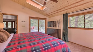 A bedroom with a large bed, wooden ceiling, a ceiling fan, a TV, and a window with blinds. - Deck + Yard: Family-friendly Pinetop Retreat (Pinetop)
