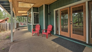 A covered porch with two red Adirondack chairs, a wooden ceiling, and a green exterior wall. - Deck + Yard: Family-friendly Pinetop Retreat (Pinetop)