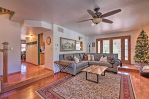 A spacious living room with a large sectional sofa, a wooden coffee table, and a Christmas tree. - Deck + Yard: Family-friendly Pinetop Retreat (Pinetop)