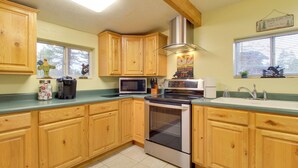 A kitchen with wooden cabinets, a microwave, an oven, and a sink. - White Mountains Hideaway! Family Cabin in Lakeside (Lakeside)