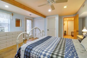 Ein Schlafzimmer mit Bett, Holzbalkendecke, Deckenventilator und einem Fenster mit Jalousien.
