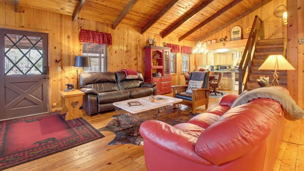 A cozy log cabin interior with a living room featuring leather sofas, a dining area, and a kitchen. - White Mountains Hideaway! Family Cabin in Lakeside (Lakeside)