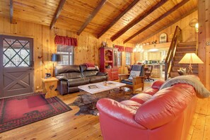 Acogedora cabaña de madera con una sala de estar que cuenta con sofás de cuero, un comedor y una cocina.