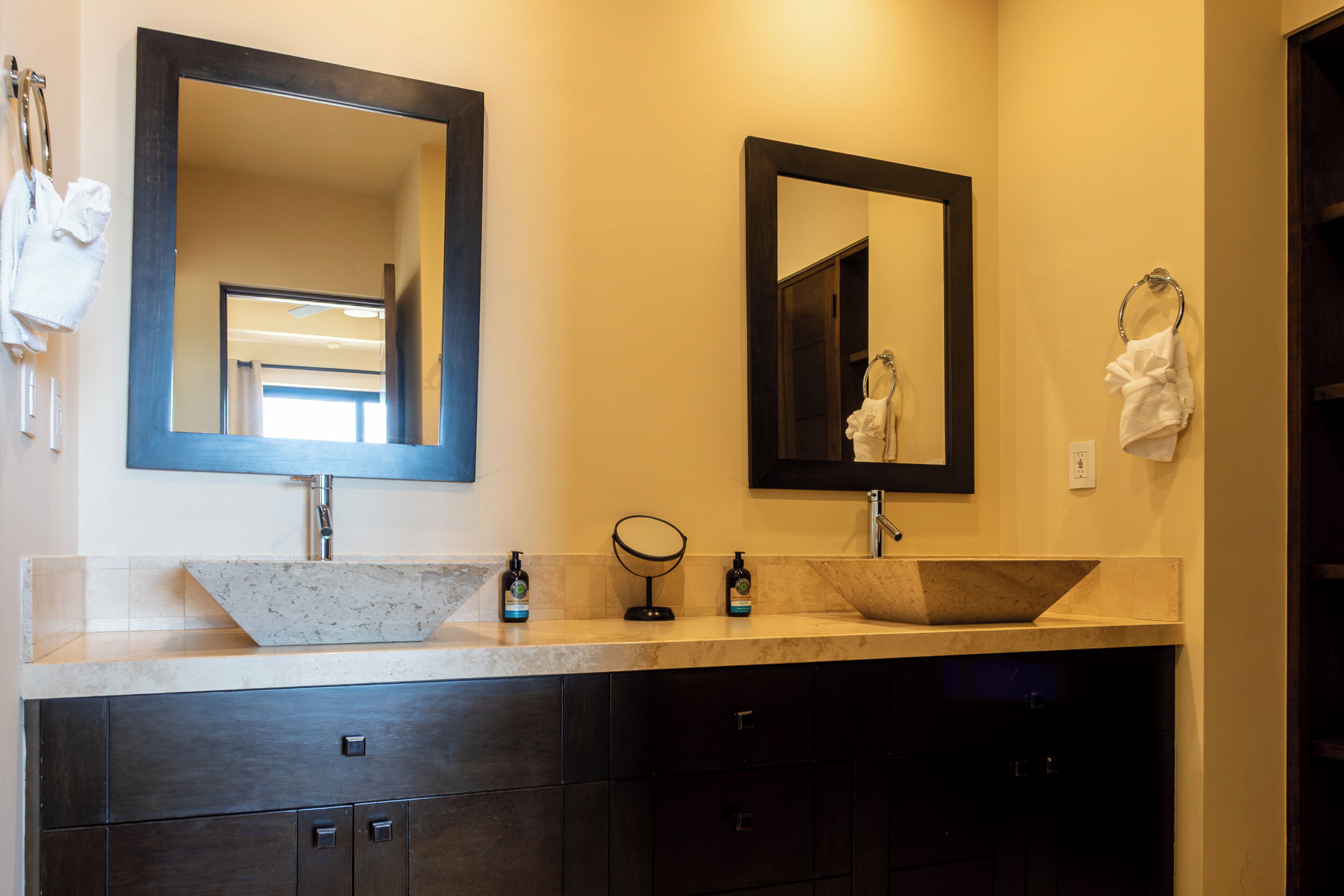A bathroom with two sinks, a large mirror, and dark cabinets.