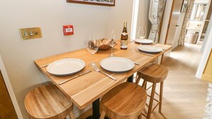 Comedor con mesa de madera dispuesta para cuatro, incluyendo platos, cubiertos y copas de vino.