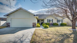 A single-story house with a garage, a front porch, and a well-maintained lawn with trimmed bushes. - Pet-friendly Nampa Vacation Rental With Yard! (Nampa)