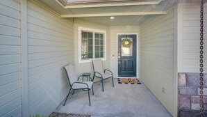 A covered porch with two chairs, a small table, and a door with a wreath. - Pet-friendly Nampa Vacation Rental With Yard! (Nampa)