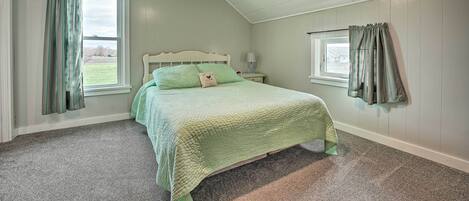 Une chambre à coucher avec un lit, une table de chevet, une fenêtre et une vue sur l’extérieur.
