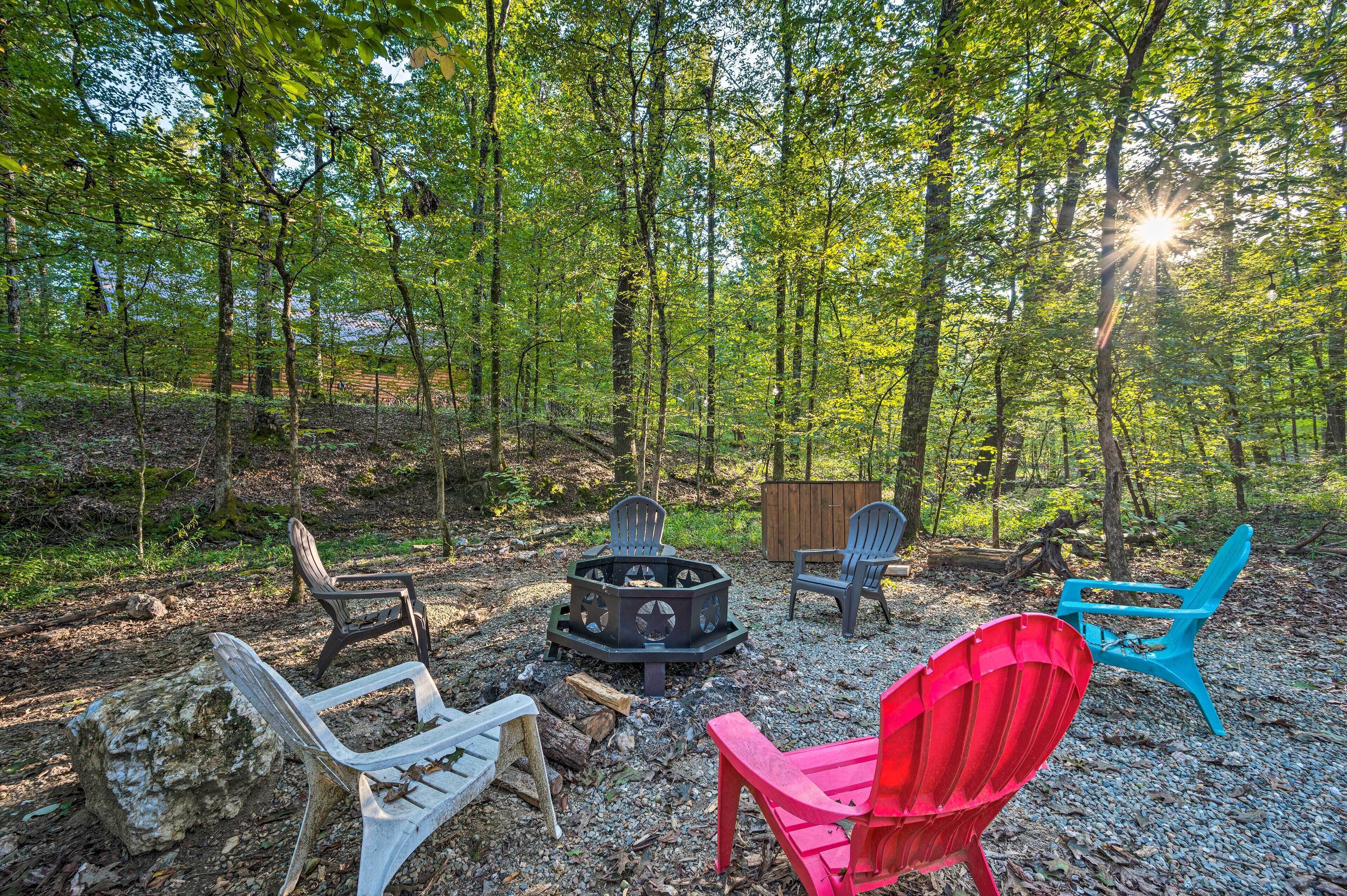 Ein bewaldetes Gebiet mit Feuerschale und mehreren Adirondack-Stühlen.
