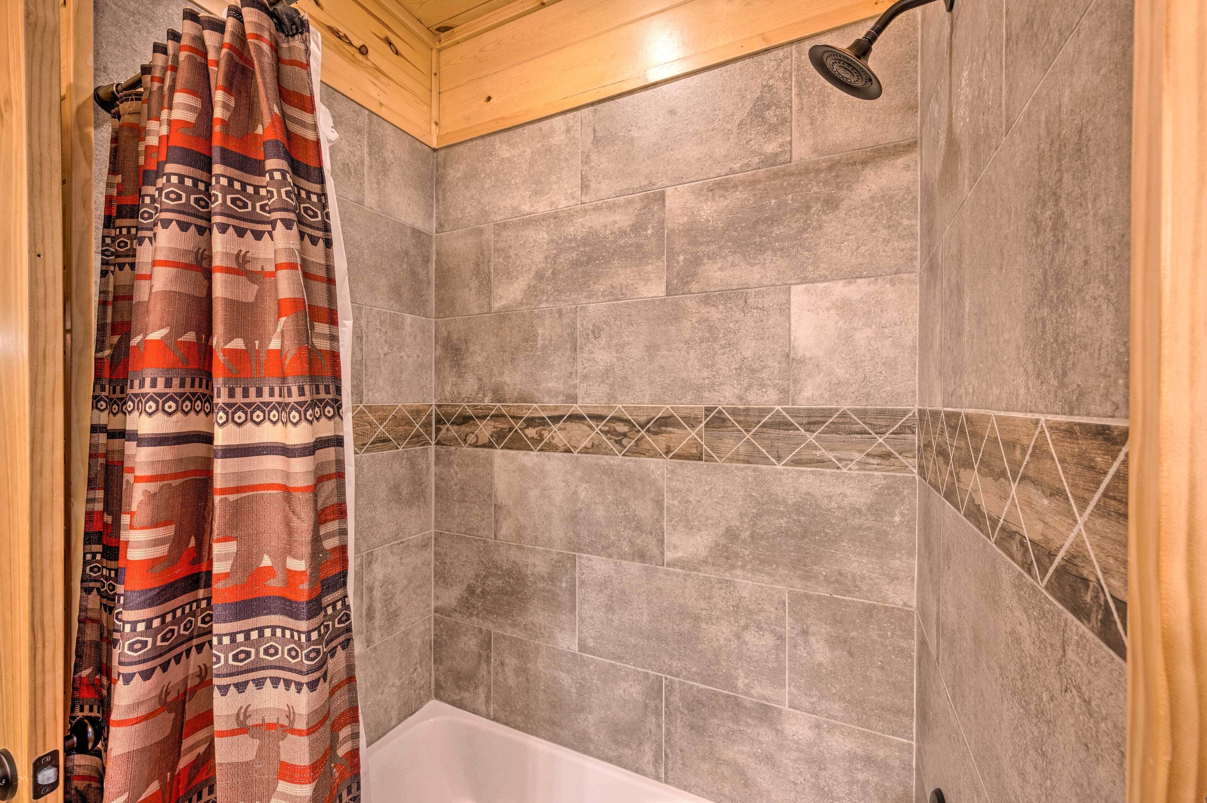 Un espace douche avec des carreaux gris et un rideau de douche à motifs.