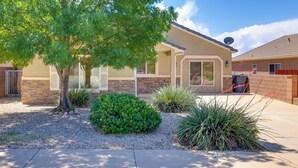 A residential house with a brick exterior, a large tree, and landscaped garden with various plants. - Family-friendly Utah Home, Easy Access to Zion! (La Verkin)