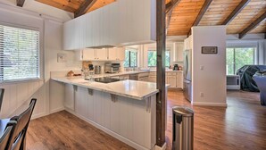 A modern kitchen with white cabinetry, a central island, and a wooden ceiling. - Deck & Grill: Camino Home in Wine Country! (Camino)