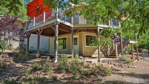 A two-story house with a balcony, a red umbrella, and a wooden deck. - Deck & Grill: Camino Home in Wine Country! (Camino)