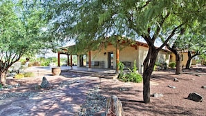A courtyard with a pergola, stone pathway, and a building with a tiled roof.