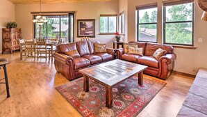 Un salon spacieux doté d’un plafond en bois, de grandes fenêtres, d’un canapé en cuir marron, d’une table basse en bois et d’un tapis à motifs.