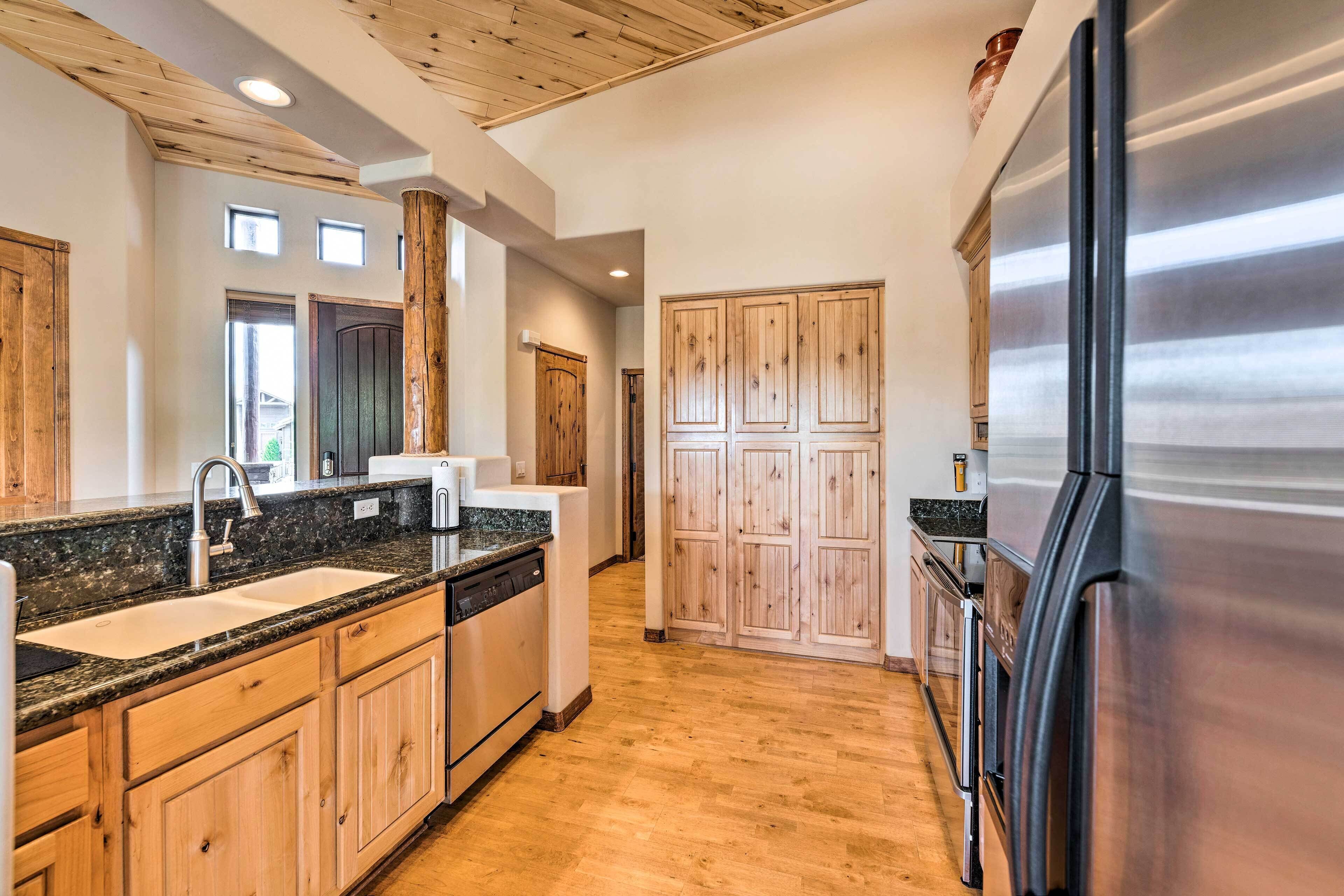 A kitchen with wooden cabinets, a stainless steel refrigerator, and a granite countertop.