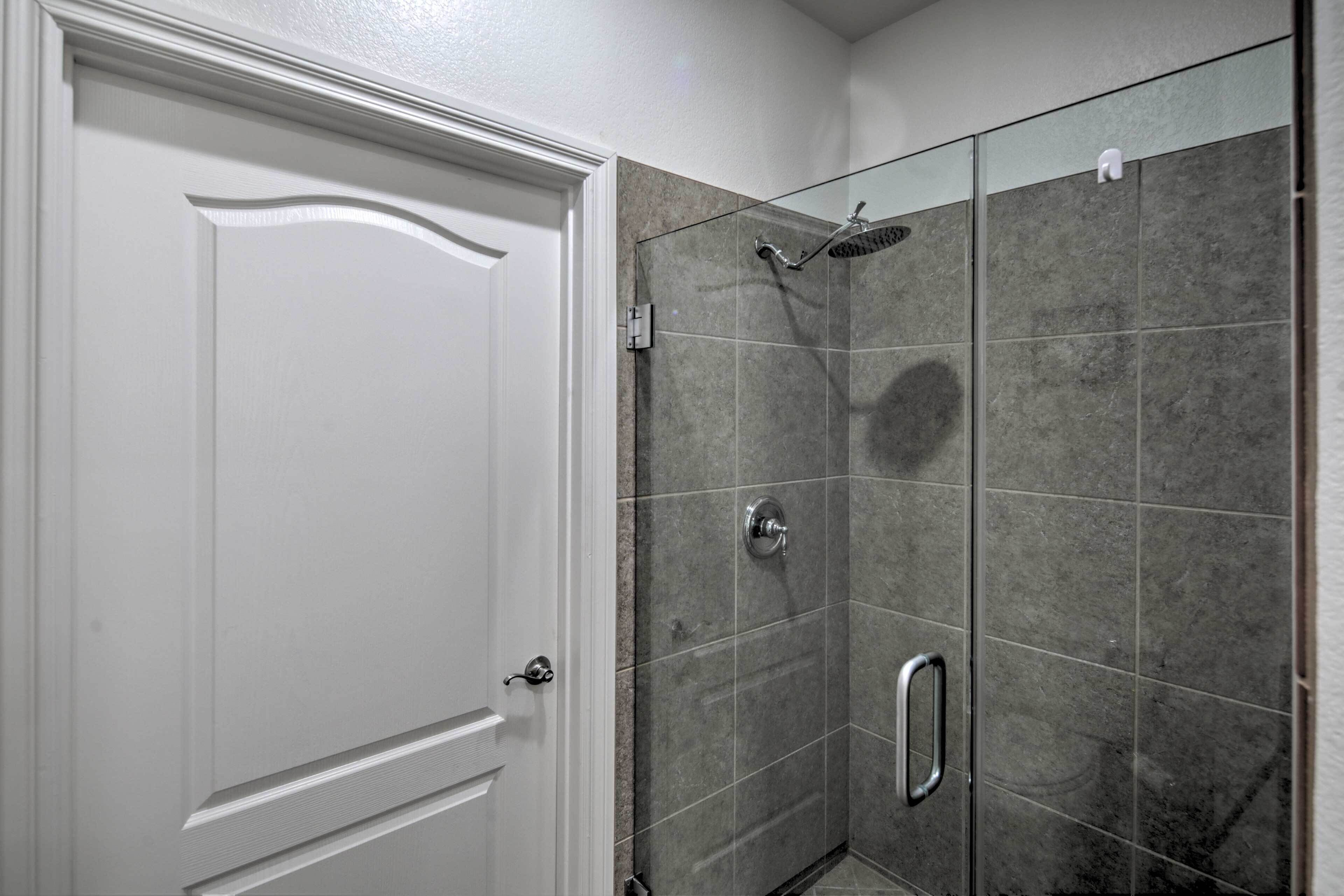 Un baño con ducha, una puerta blanca y paredes con azulejos.
