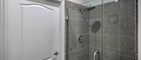 Un baño con ducha, una puerta blanca y paredes con azulejos.