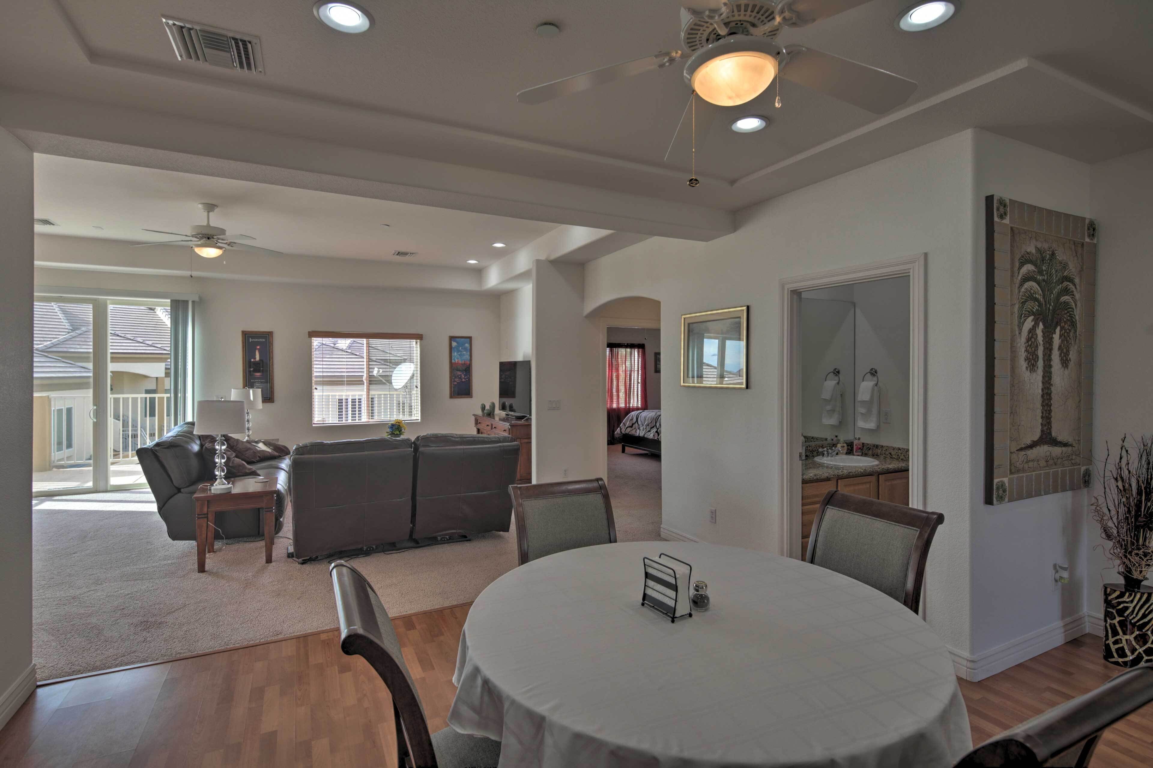 A spacious living area with a dining table, sofas, and a ceiling fan.