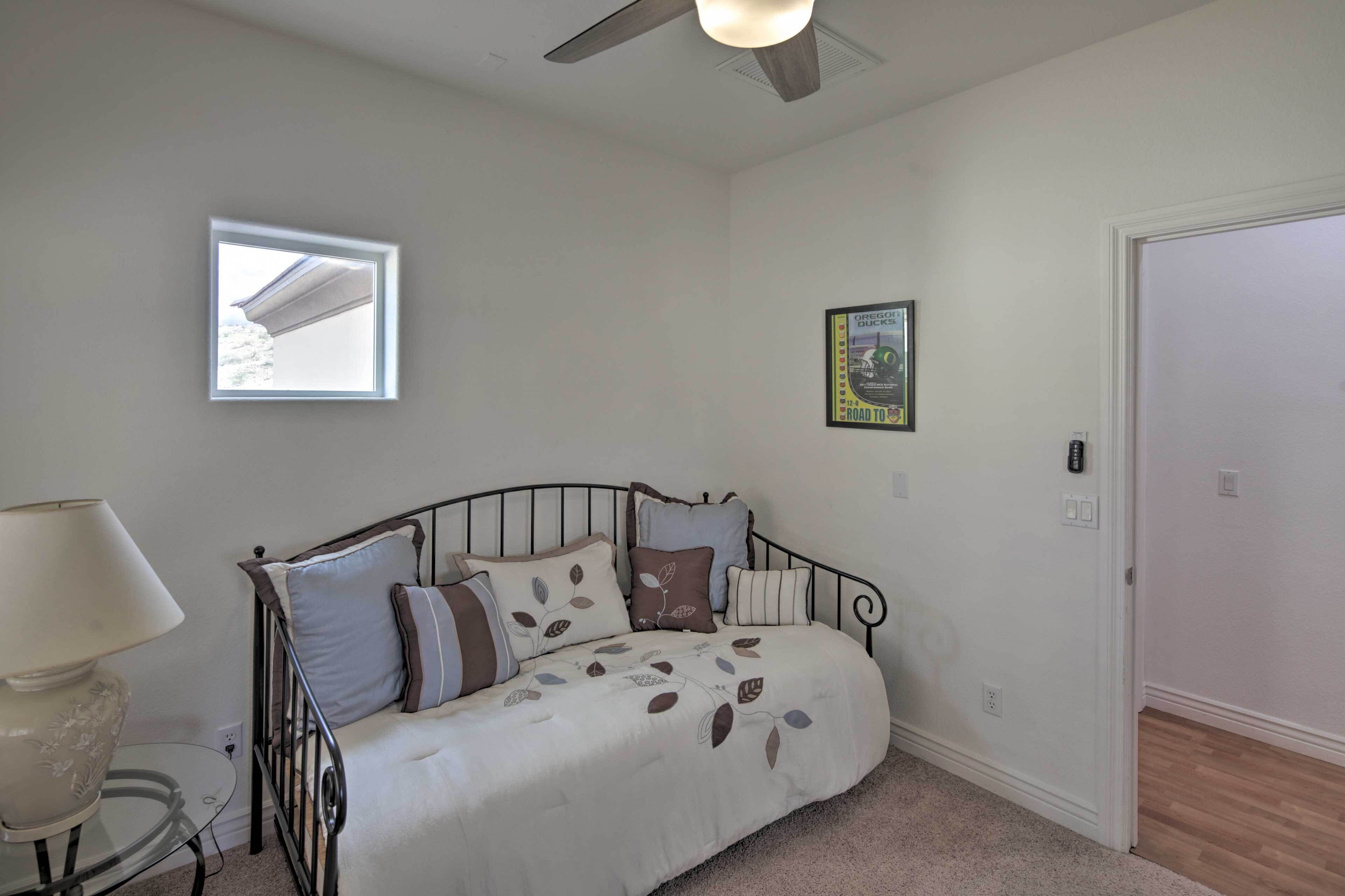 A bedroom with a bed, a bedside table, a lamp, a window, and a door.