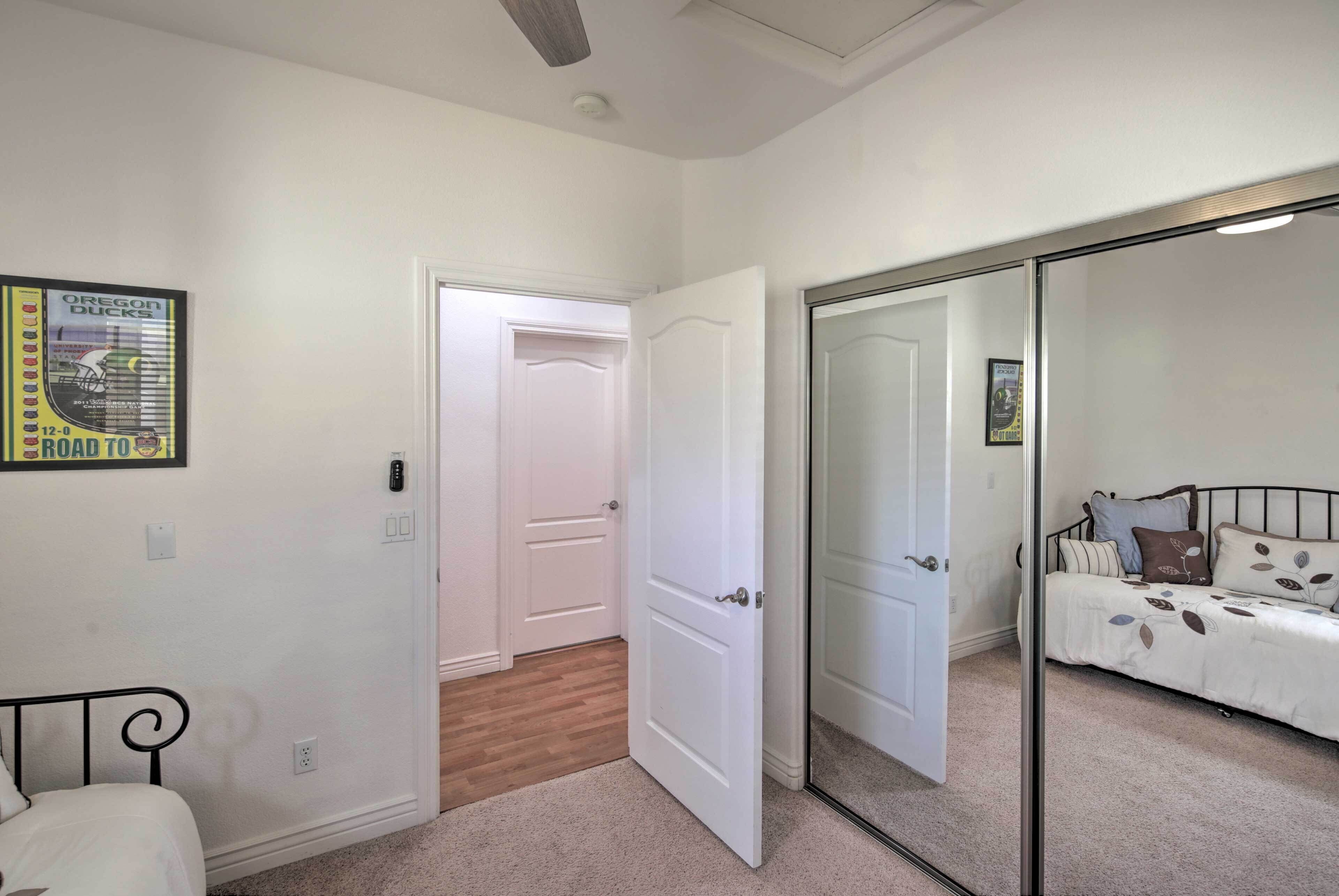 A bedroom with a bed, a door, a mirror, and a poster on the wall.