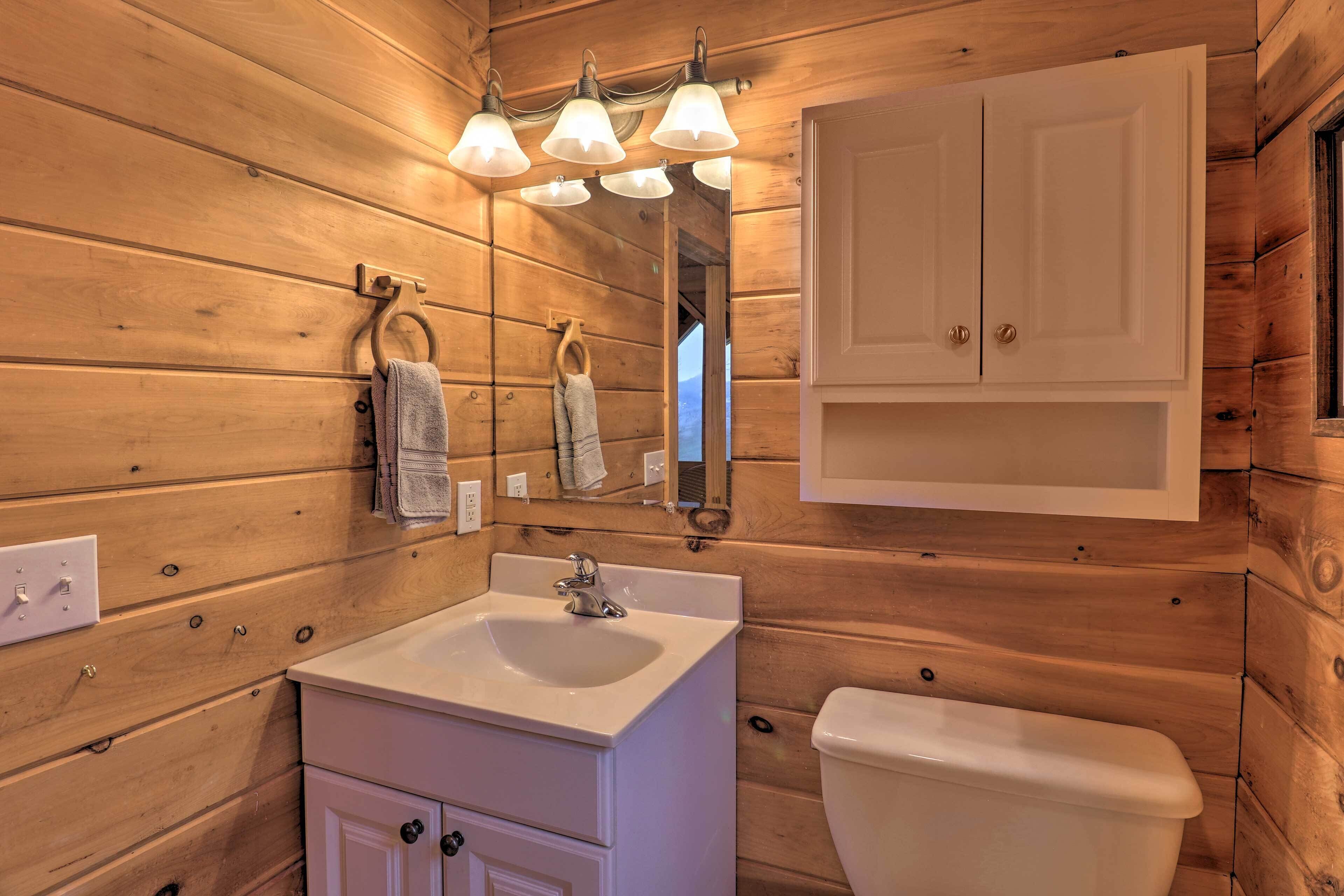 A wooden cabin bathroom with a white sink, a mirror, and a toilet.