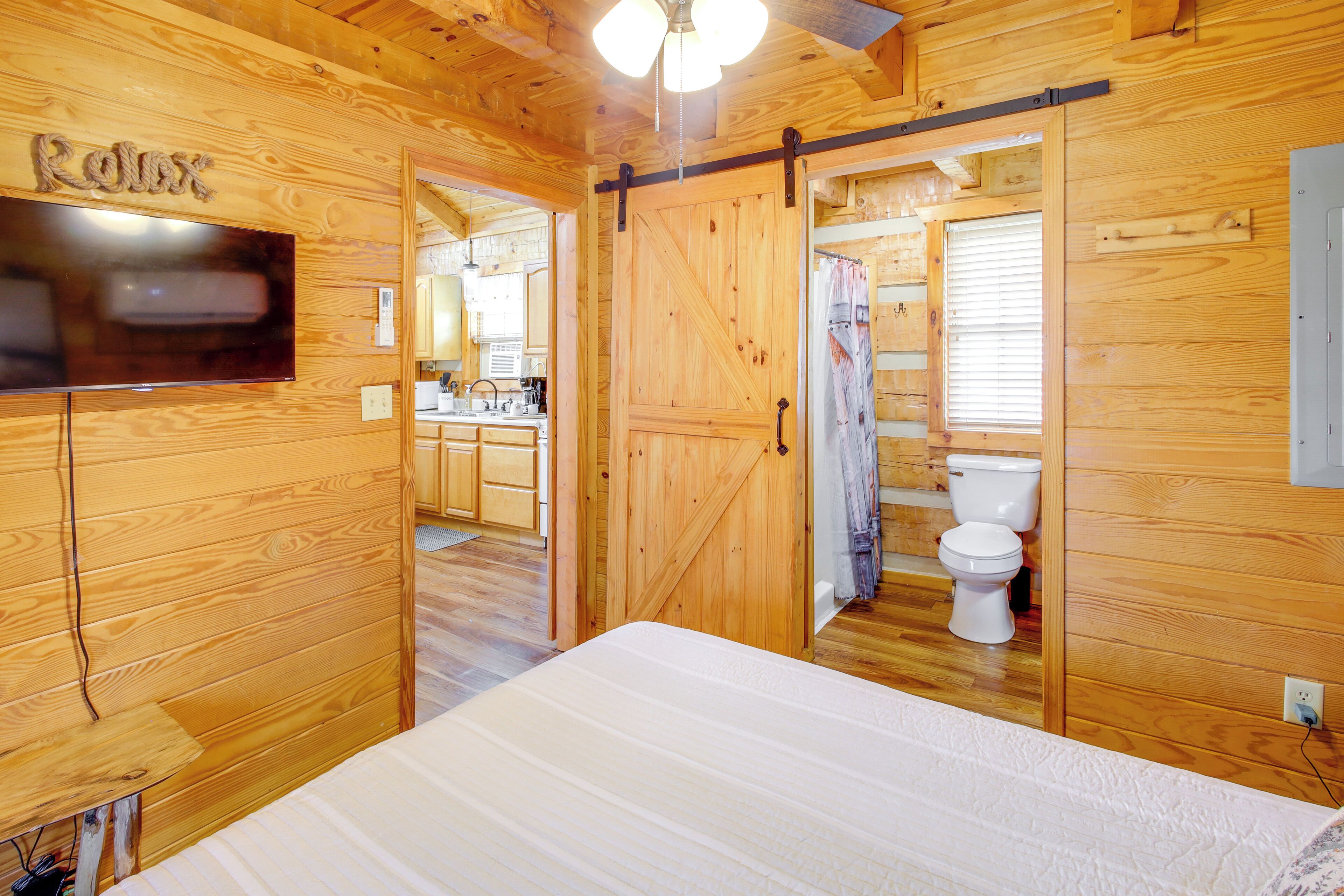 L’intérieur d’une cabane en bois comprend un lit, un téléviseur, un coin cuisine et une salle de bain.