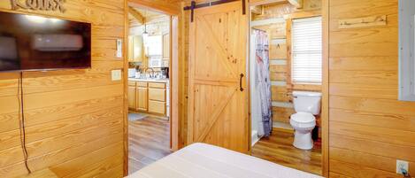 L’intérieur d’une cabane en bois comprend un lit, un téléviseur, un coin cuisine et une salle de bain.