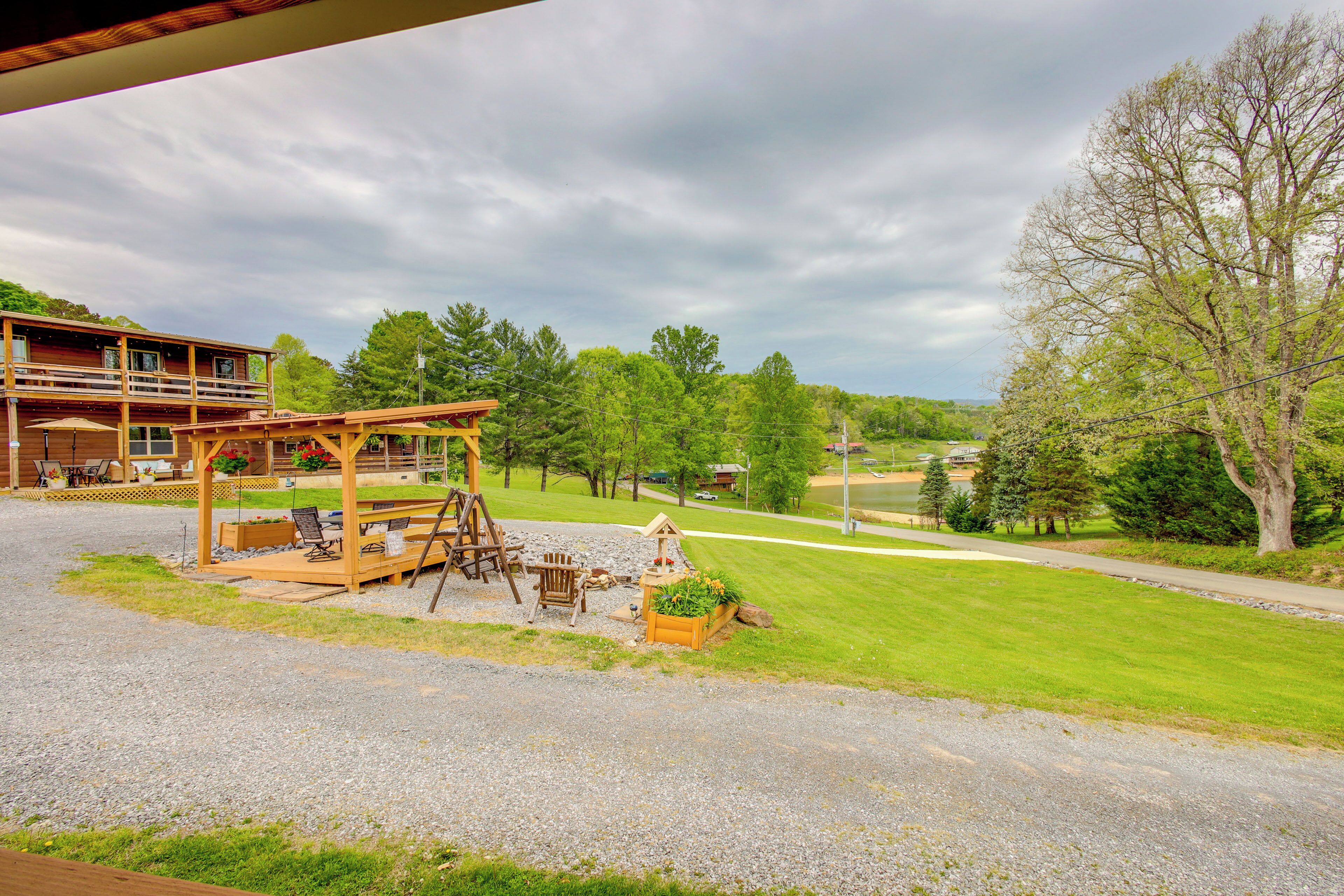 A two-story wooden cabin with a deck, outdoor seating, and a swing set.