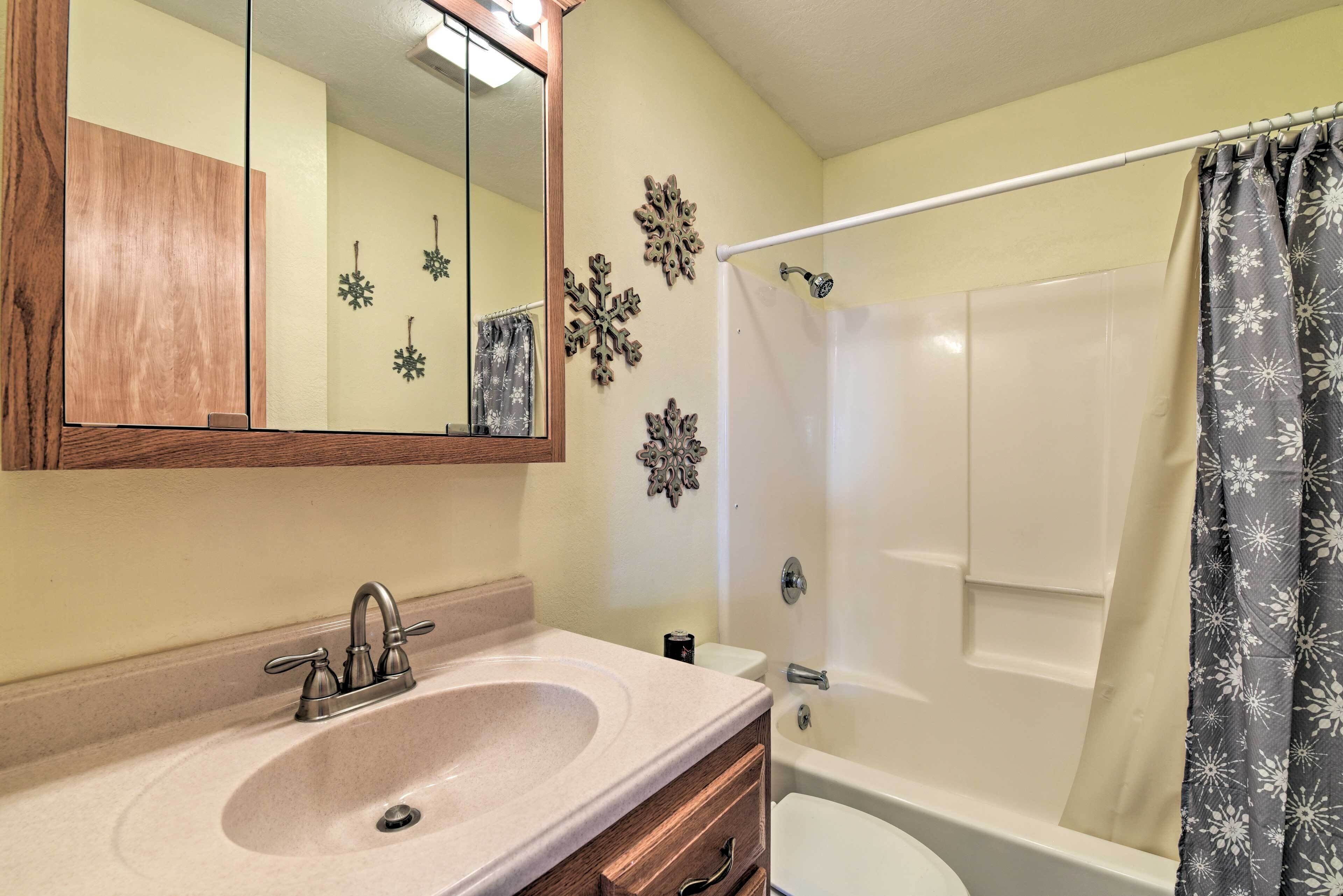 A bathroom with a sink, mirror, toilet, and bathtub.