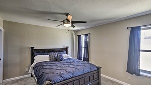 A bedroom with a dark wooden bed, a ceiling fan, and a window with blue curtains. - Near Marina: Home w/ Pool & Views in Lake Havasu! (Lake Havasu City)