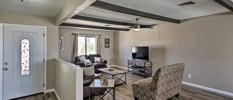 Amplia sala de estar con chimenea, televisor y zona de estar con un sillón estampado y un sofá.