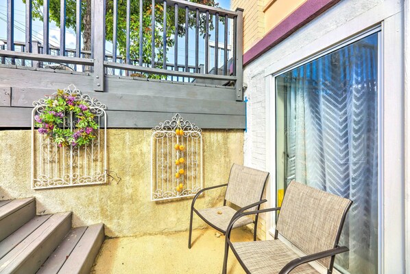 A balcony with a wooden railing, a chair, and a window with a patterned curtain. - Cincinnati Basement Unit ~ 10 Mi to Downtown! (Cincinnati)
