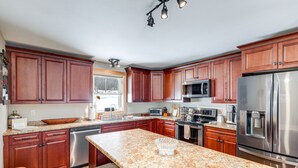 Uma cozinha moderna com bancadas de granito, eletrodomésticos de aço inoxidável e armários de madeira.