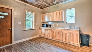 Une cuisine avec des meubles de rangement en bois, un four à micro-ondes, un évier et un ventilateur de plafond.