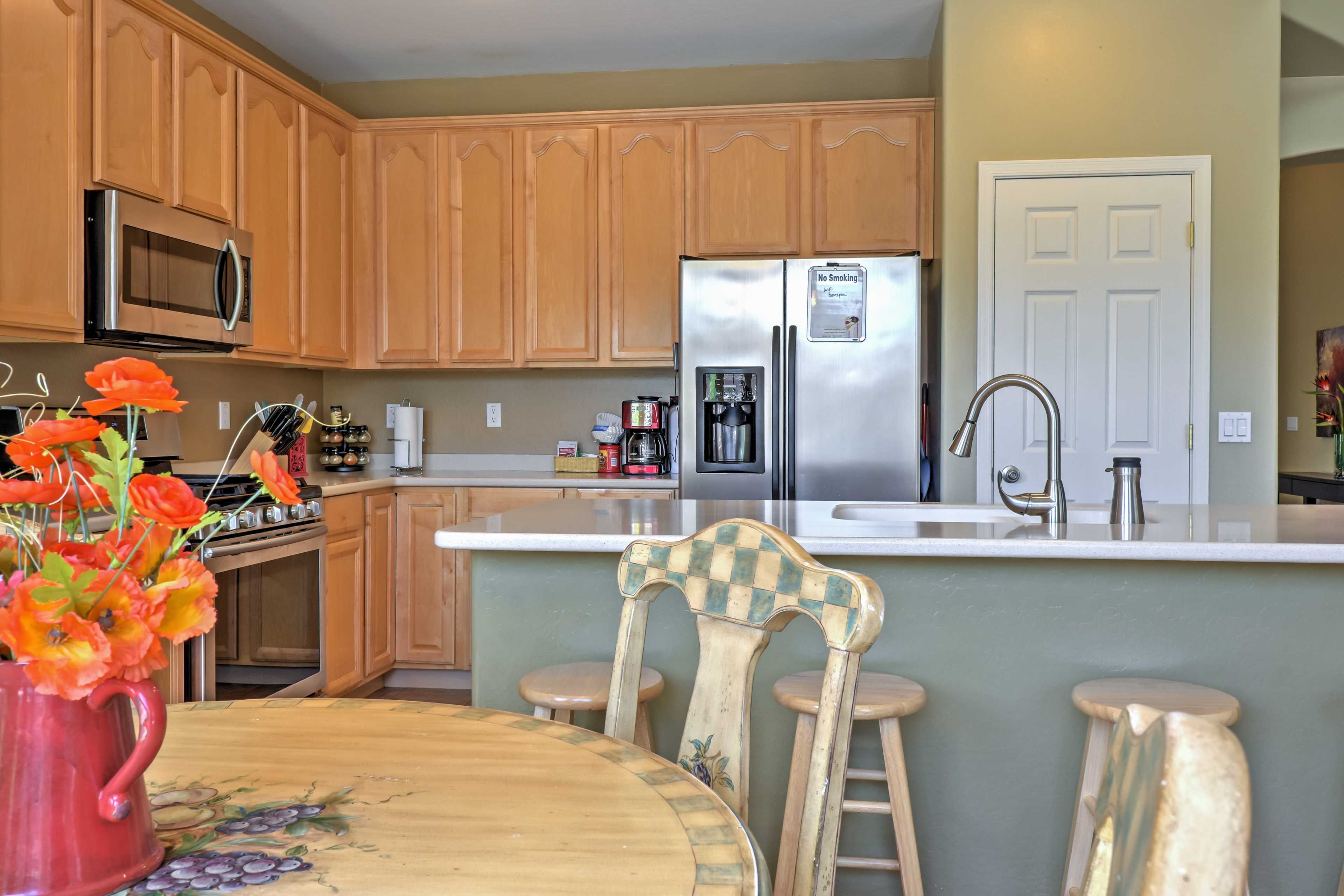 A kitchen with wooden cabinets, a stainless steel refrigerator, a microwave, and a coffee maker.