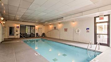 Piscina interior com faixas de separação bem definidas, cadeira do salva-vidas e aviso proibindo saltos.