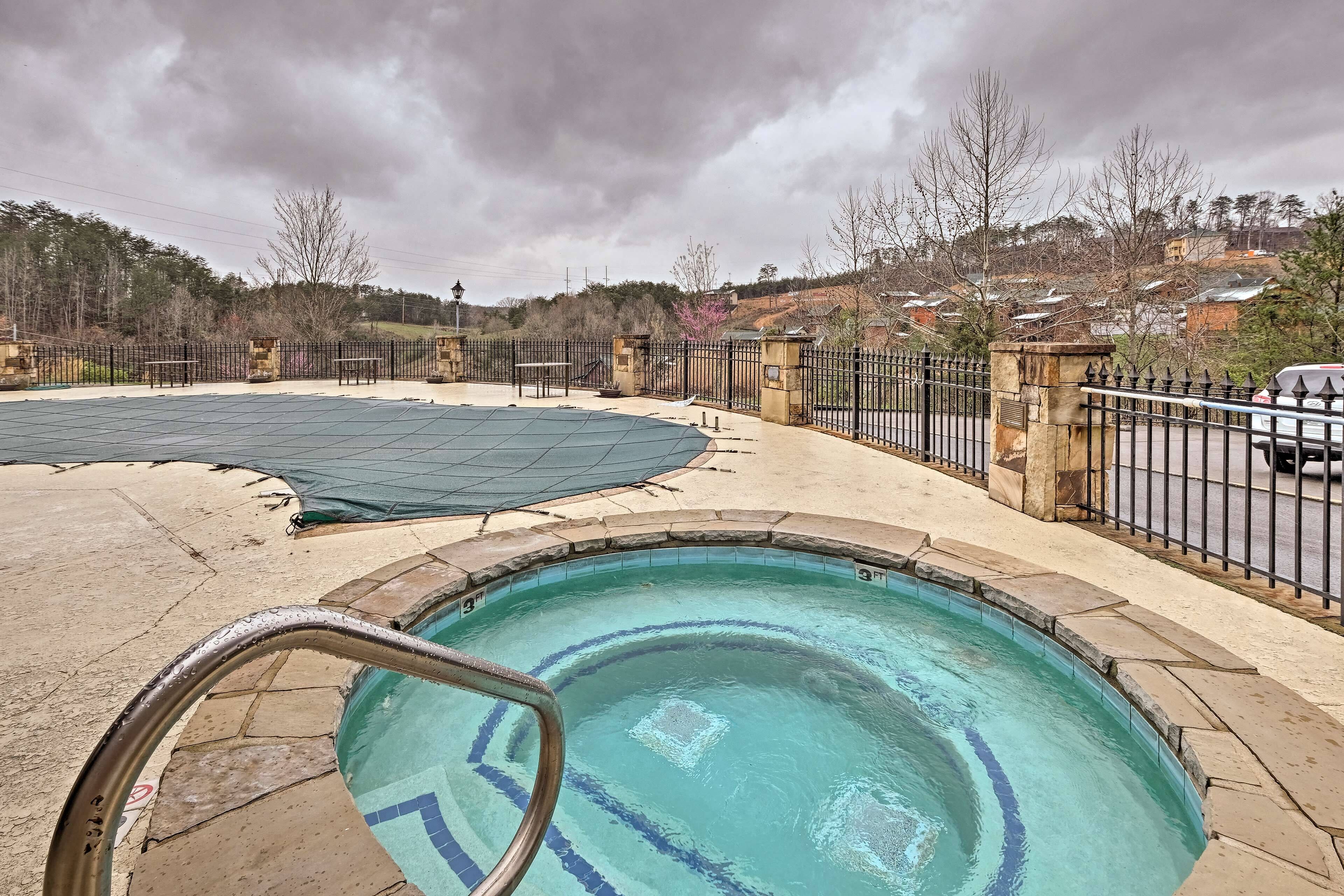 A swimming pool with a tiled deck, a metal ladder, and a surrounding fence.