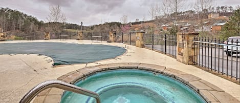 A swimming pool with a tiled deck, a metal ladder, and a surrounding fence.