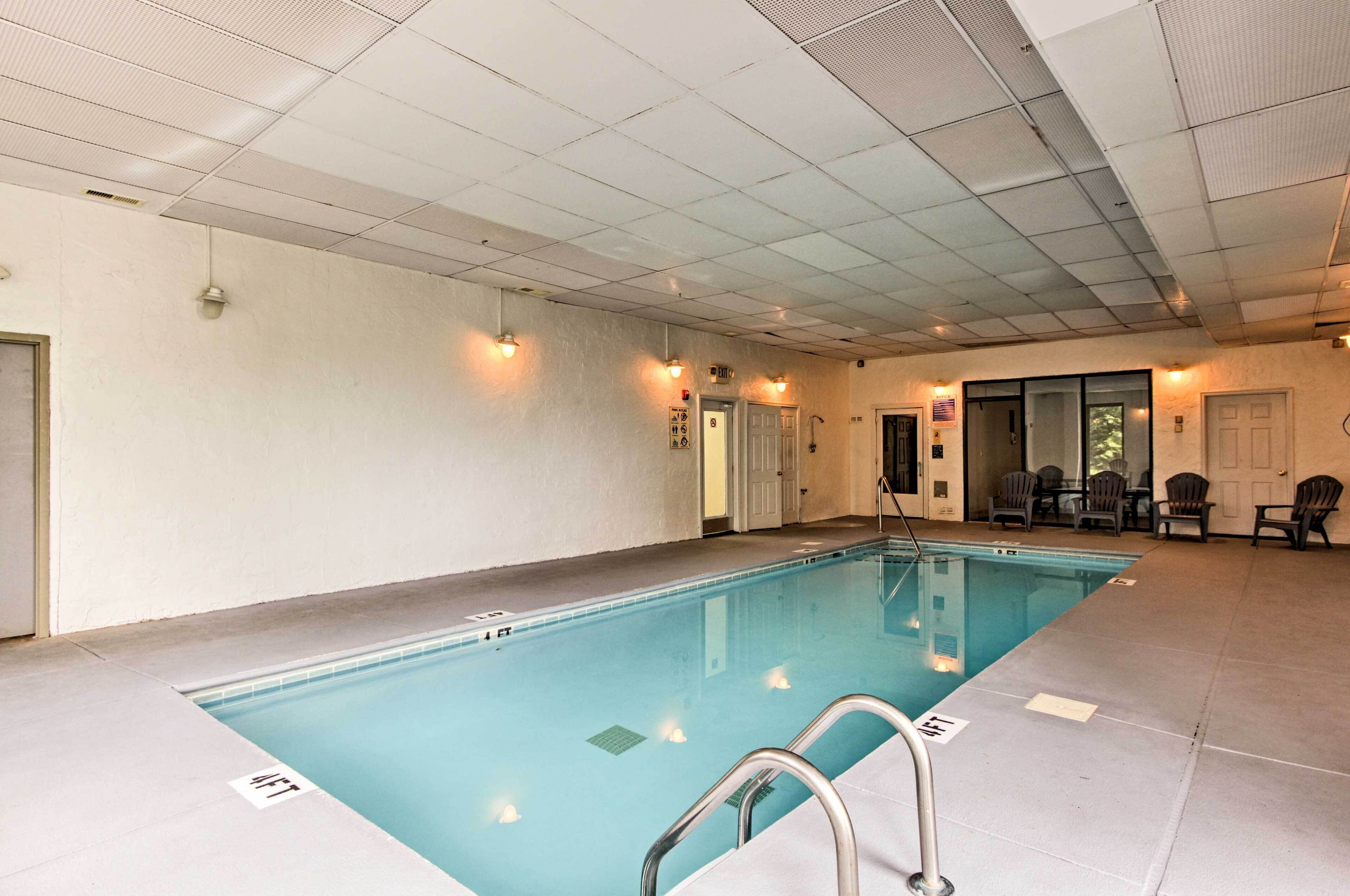 An indoor swimming pool with clear water, a metal ladder, and a tiled floor.