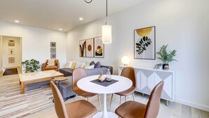 A modern living room with a round white table, brown leather chairs, a grey sofa, and a white cabinet with geometric patterns. - Beautiful Townhome - Steps to Downtown Boise! (Boise)