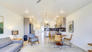 A modern living room with a sofa, chairs, and a dining table. There is a kitchen in the background with appliances and a dining area. - Beautiful Townhome - Steps to Downtown Boise! (Boise)