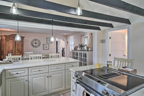 A kitchen with a large island, a stove, and hanging pendant lights. - Charming Cape Charles Vacation Rental Home! (Cheriton)