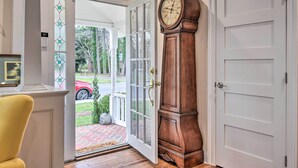 A grand wooden grandfather clock next to a white door with a glass entrance. - Charming Cape Charles Vacation Rental Home! (Cheriton)