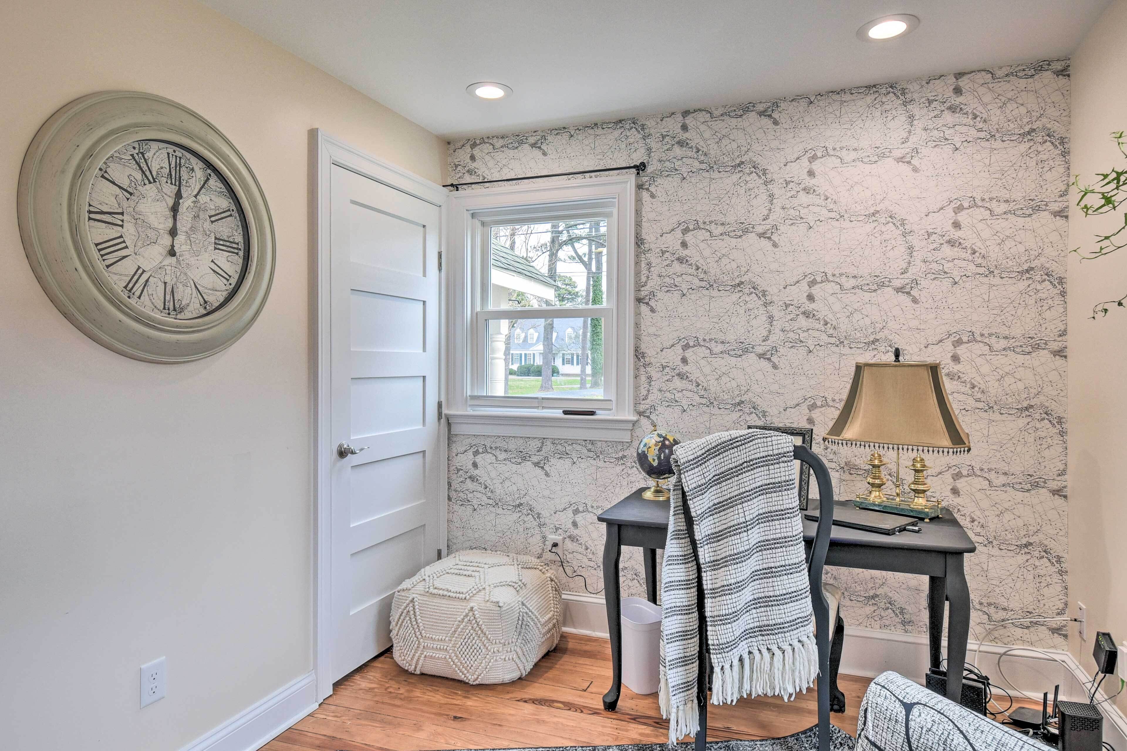 Une pièce avec un mur décoré d’un motif imitant le marbre, une horloge murale ronde, une fenêtre, une petite table avec une lampe et une chaise.